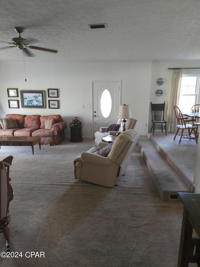 living room with ceiling fan, dark carpet, and a textured ceiling