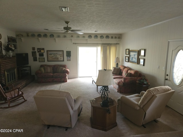 carpeted living room with a brick fireplace, a textured ceiling, and ceiling fan