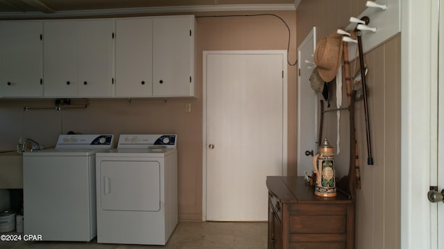 laundry room featuring ornamental molding, washer and clothes dryer, and cabinets