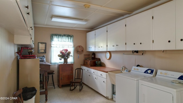 clothes washing area featuring washer and dryer, wood walls, and cabinets