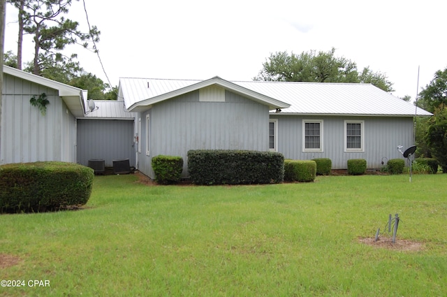 back of house featuring central AC unit and a lawn