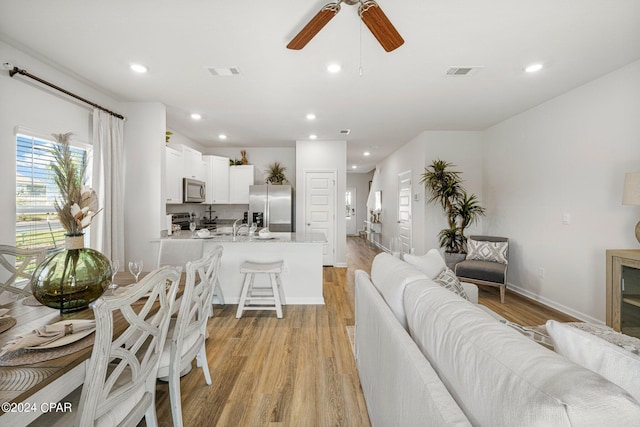 living room with ceiling fan, sink, and light wood-type flooring