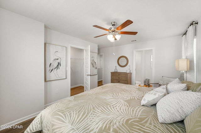 bedroom featuring wood-type flooring, a spacious closet, a closet, and ceiling fan