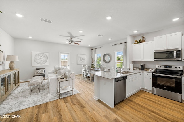 kitchen featuring sink, light wood-type flooring, stainless steel appliances, white cabinets, and light stone countertops