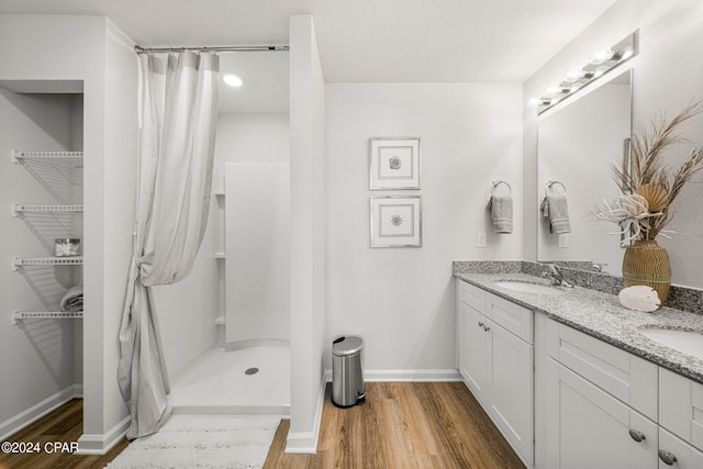 bathroom featuring vanity, curtained shower, wood-type flooring, and a textured ceiling