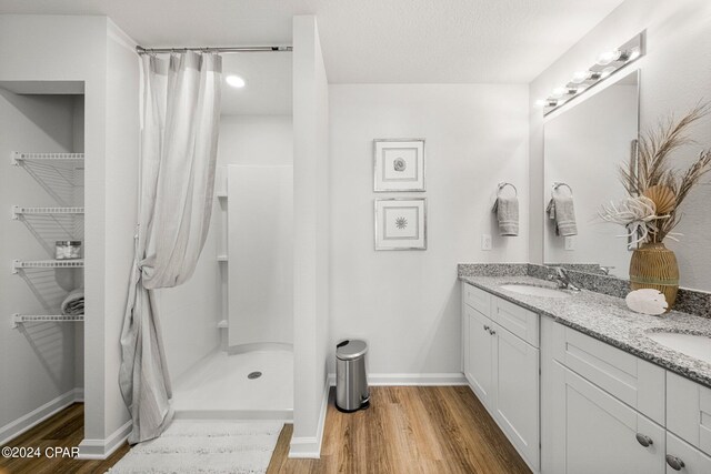 bathroom with curtained shower, vanity, wood-type flooring, and a textured ceiling