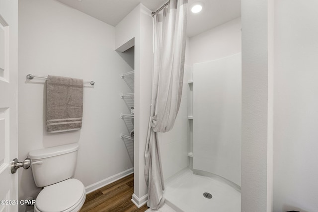 bathroom with a shower with shower curtain, hardwood / wood-style flooring, and toilet