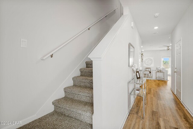 stairway featuring ceiling fan and wood-type flooring