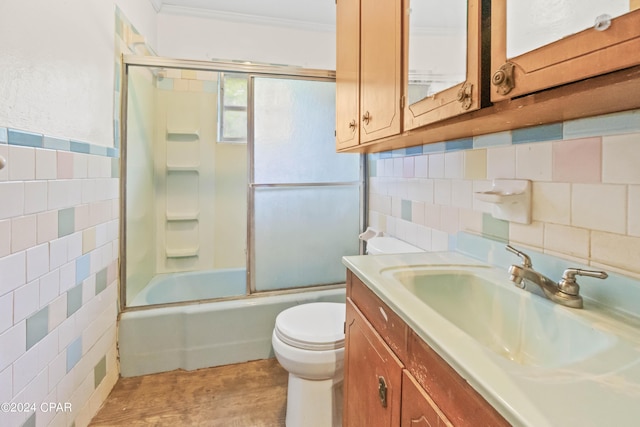 full bathroom with combined bath / shower with glass door, crown molding, toilet, vanity, and tile walls