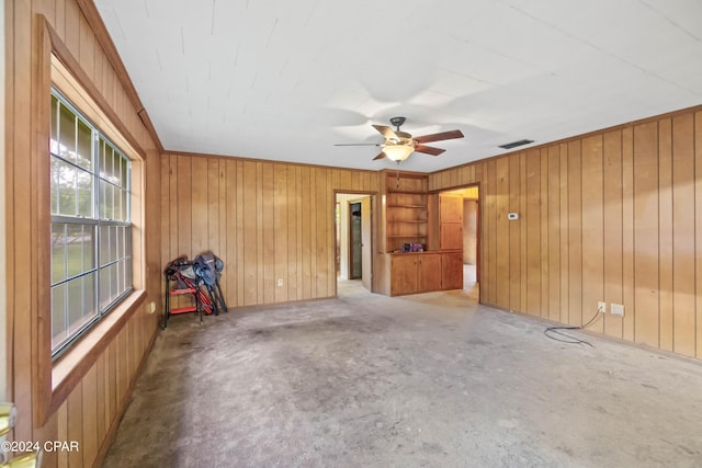 unfurnished room with ceiling fan, wooden walls, and carpet