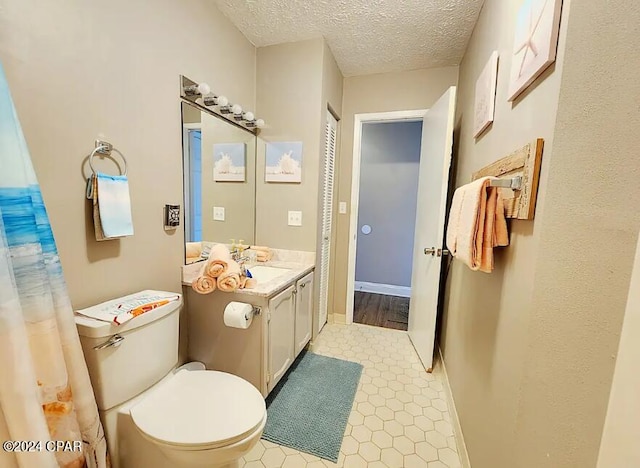 bathroom with a textured ceiling, vanity, toilet, and baseboards