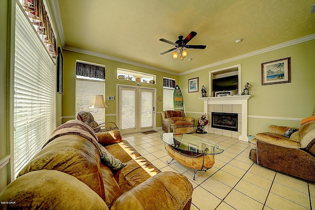 living room with a tile fireplace, a textured ceiling, ceiling fan, and light tile patterned flooring