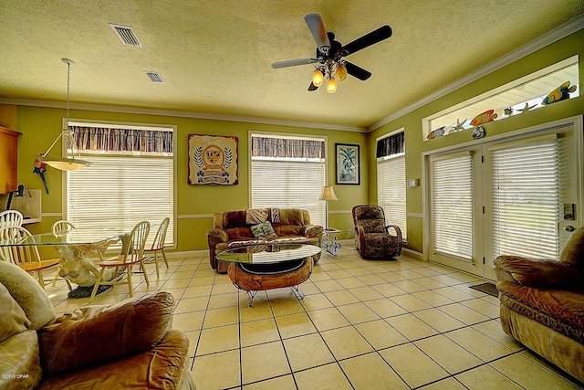 living room with ceiling fan, crown molding, light tile patterned floors, and a textured ceiling