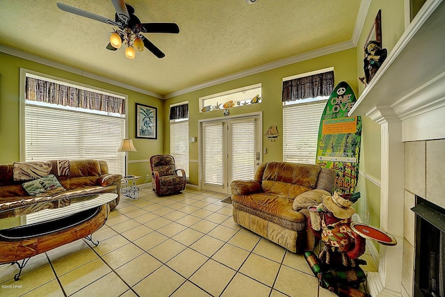 living room featuring a tile fireplace, ceiling fan, light tile patterned floors, and a textured ceiling