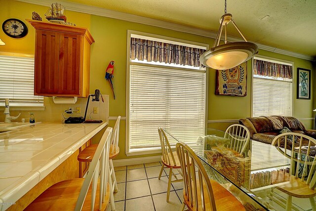 dining area with sink, light tile patterned floors, a textured ceiling, and ornamental molding