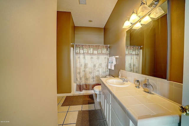 full bathroom featuring vanity, a textured ceiling, shower / bath combo with shower curtain, tile patterned flooring, and toilet