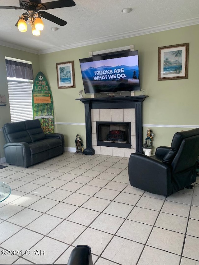 tiled living room featuring a tile fireplace, ceiling fan, a textured ceiling, and ornamental molding