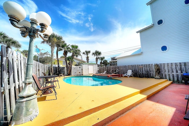 view of swimming pool with a patio area and a storage shed