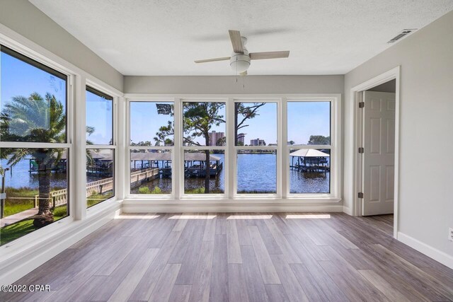 unfurnished sunroom featuring ceiling fan, a healthy amount of sunlight, and a water view