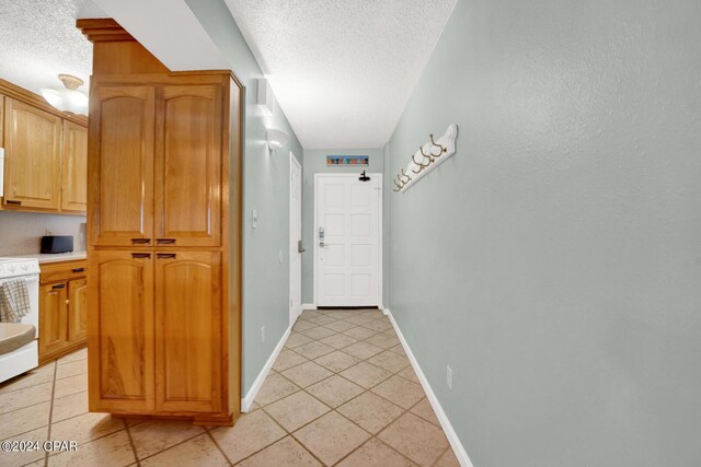 corridor featuring a textured ceiling and light tile patterned floors