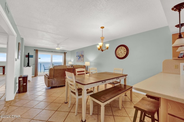 dining area featuring ceiling fan with notable chandelier, a textured ceiling, and light tile patterned flooring