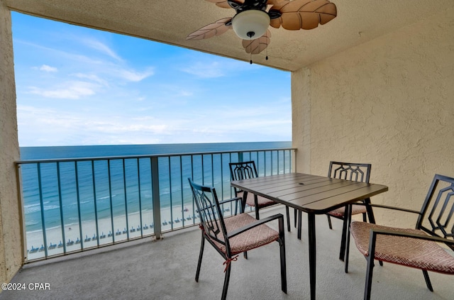 balcony with a water view, ceiling fan, and a beach view