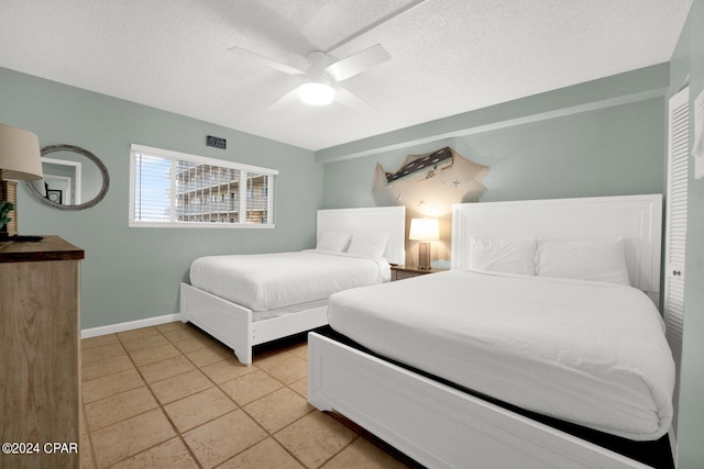 bedroom with ceiling fan, light tile patterned floors, and a textured ceiling