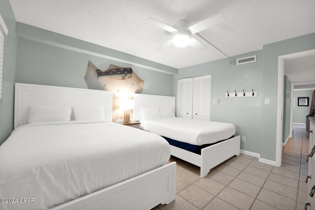 bedroom with light tile patterned flooring, ceiling fan, a textured ceiling, and a closet