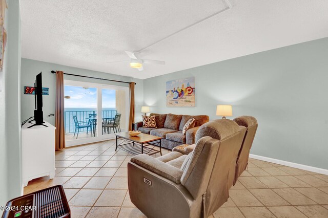 living room featuring a textured ceiling, light tile patterned floors, and ceiling fan