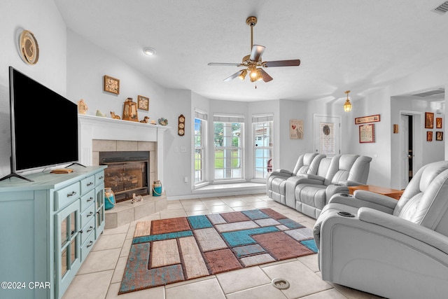 tiled living room featuring ceiling fan, a textured ceiling, and a fireplace