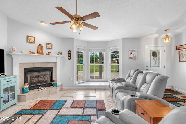 tiled living room featuring ceiling fan, a textured ceiling, and a tile fireplace