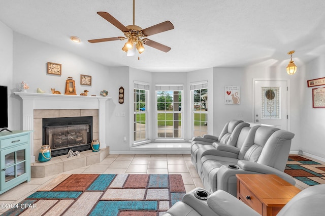 tiled living room featuring a tiled fireplace, ceiling fan, and a textured ceiling