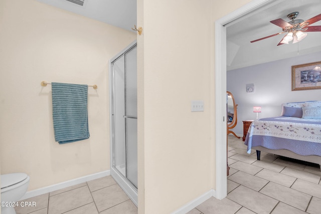 bathroom featuring ceiling fan, toilet, a shower with shower door, and tile patterned flooring