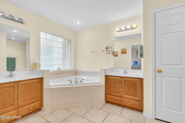 bathroom featuring tile patterned flooring, vanity, and tiled bath