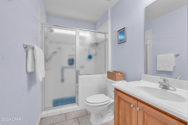 bathroom with vanity, toilet, a shower with shower door, and tile patterned flooring