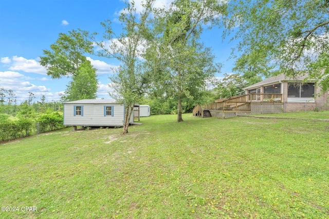 view of yard featuring a storage unit, a deck, and a sunroom