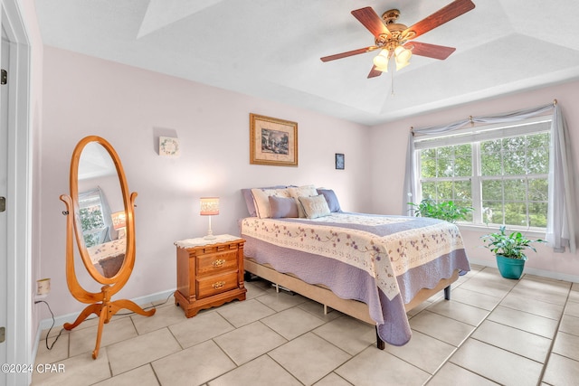 tiled bedroom with ceiling fan and a tray ceiling