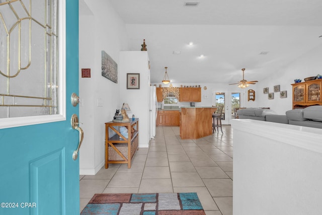 entrance foyer with light tile patterned floors, vaulted ceiling, and ceiling fan