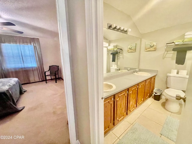 bathroom with ceiling fan, vanity, lofted ceiling, toilet, and tile patterned flooring