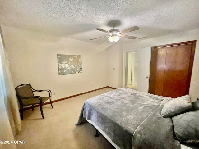 carpeted bedroom with ceiling fan, a textured ceiling, and a closet