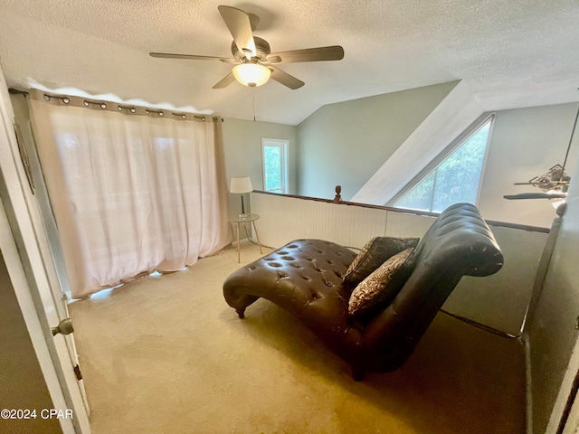 living area with a textured ceiling, vaulted ceiling, light carpet, and ceiling fan