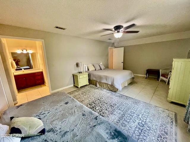 bedroom with ceiling fan, a textured ceiling, connected bathroom, and light tile patterned flooring