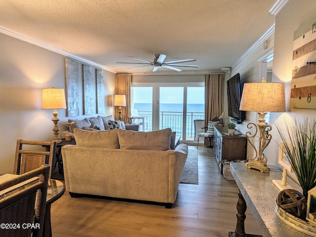 living room featuring ceiling fan, crown molding, hardwood / wood-style flooring, and a water view