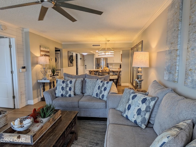 living room featuring hardwood / wood-style flooring, a textured ceiling, ceiling fan with notable chandelier, and crown molding