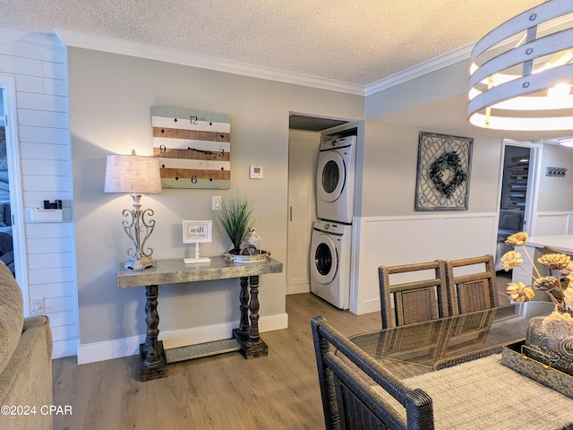 interior space featuring stacked washer and clothes dryer, crown molding, a textured ceiling, and wood-type flooring