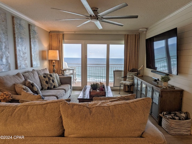 living room with a water view, ceiling fan, a textured ceiling, and crown molding