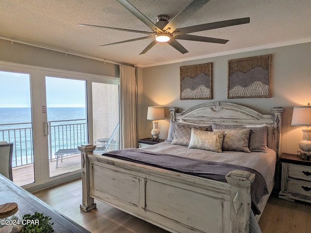 bedroom with ceiling fan, crown molding, a water view, wood-type flooring, and access to exterior