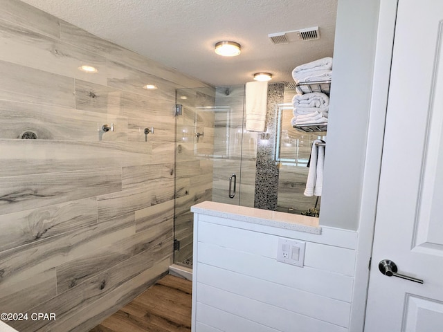 bathroom featuring walk in shower, hardwood / wood-style flooring, and a textured ceiling