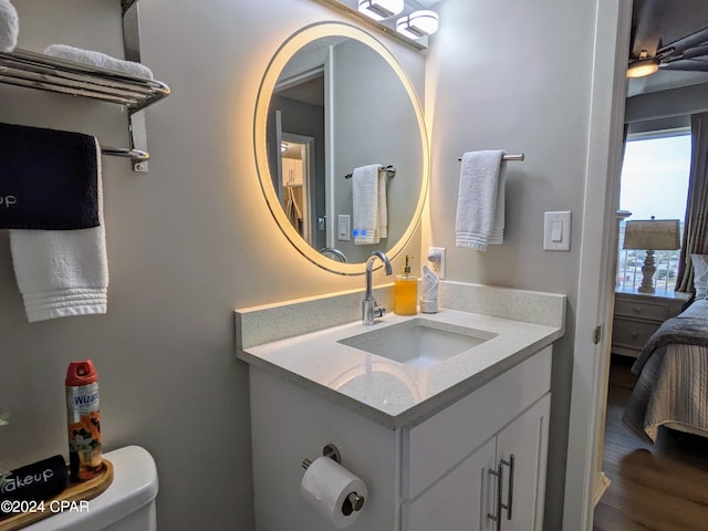 bathroom with vanity with extensive cabinet space, toilet, and hardwood / wood-style floors