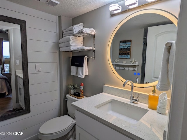 bathroom with a textured ceiling, vanity, and toilet